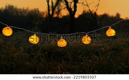 Orange glowing jack-o' lanterns garland on dark mysterious natural background. symbol of Halloween holiday, Samhain sabbat. autumn season. template for design