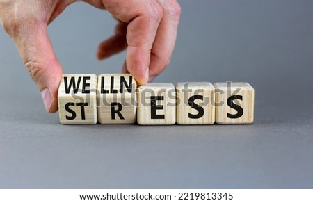 Stress or wellness symbol. Concept words Stress or Wellness on wooden cubes. Businessman hand. Beautiful grey table grey background. Business stress or wellness concept. Copy space.