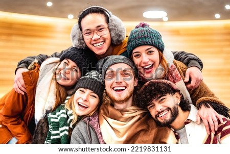 Happy multiracial guys and girls taking selfie on warm fashion clothes - Trendy life style concept with millenial people having fun together indoors on winter holidays - Bright vivid filter