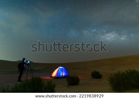 Photographer taking Milky way night sky photo in desert sand dune, night off road night camping.