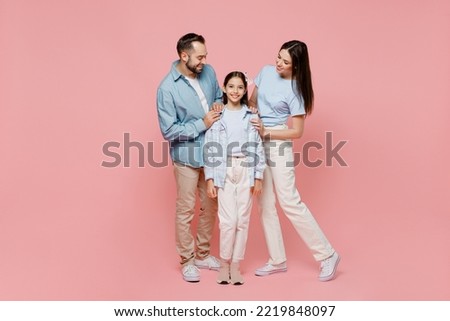Full body young happy caucasian smiling fun parents mom dad with child kid daughter teen girl in blue clothes look camera hug cuddle isolated on plain pastel light pink background. Family day concept