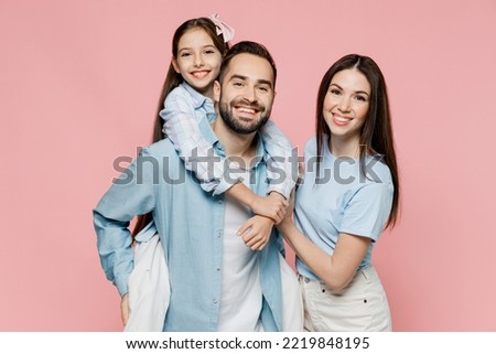 Young parents mom dad with child kid daughter teen girl in blue clothes giving piggyback ride to kid, sit on back isolated on plain pastel light pink background Family day parenthood childhood concept Royalty-Free Stock Photo #2219848195