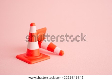 Attention, under construction, maintenance or repair concept. Close up single orange white traffic warning cone or pylon on pink background with copy space.