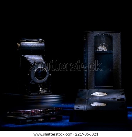 Composition of old vhs cassettes, cassette tapes and an antique bellows camera