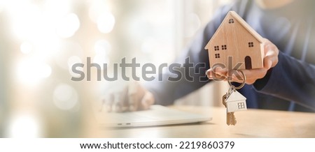 Businessman choosing mini wood house model from model and row of coin money on wood table, selective focus, Planning to buy property. 