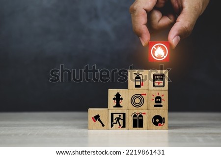 Hand choose cube wooden block stack with fire prevent icon with fire extinguisher for emergency protection and safety or rescue concepts in the building. Royalty-Free Stock Photo #2219861431