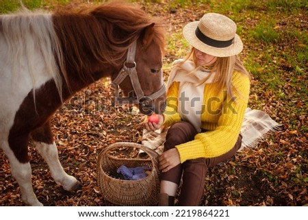 Beautiful portrait, woman and pony, spotted horse, in autumn forest, pleasant colors, background. concept of love, tenderness, friendship. eats an apple