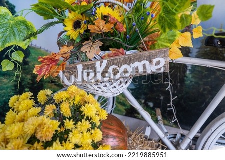 Text welcome on a wooden board with flowers on the street in the Carpathian mountain village, Ukraine. Welcome wooden sign inscription, close up