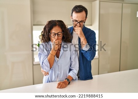 Middle age couple standing together feeling unwell and coughing as symptom for cold or bronchitis. health care concept.  Royalty-Free Stock Photo #2219888415