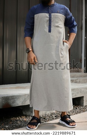 young Asian man posing with modern design of thobe. modern Moslem Wear. common arabian man's fashion Royalty-Free Stock Photo #2219889671