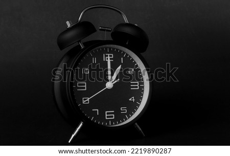 remote image of The black alarm clock is set to 1:00 a.m. on a dark background