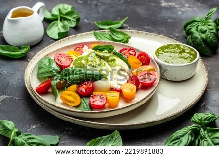 Salad burrata cheese tomatoes and green pesto. Delicious balanced food concept. superfood concept. Healthy, clean eating. Vegan or gluten free diet. top view.
