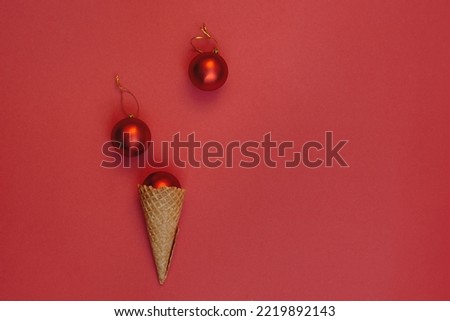 New Year decoration balls in a waffle cone on a red background. Round toys with gold thread. Alternative concept of celebrating winter holidays, top view festive composition. Lying flat
