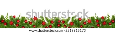 Winter bottom border with evergreen branches and red Christmas decorations. Top view isolated on a white banner background.