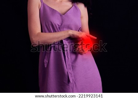 young woman experiencing pain in the wrist joint on black background.