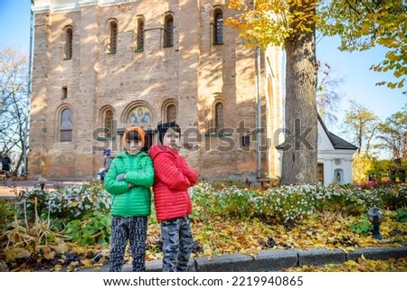 Young brothers near an ancient stone church. Kids smiling and happy having leisure time on autumn holiday. Travel with children concept.
