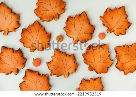 Gingerbread cookies with orange icing in the shape of fallen autumn leaves freshly baked out of the oven. Thanksgiving Day or Halloween festive background. Flat lay. White background