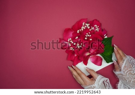 Women's hands hold an envelope with rose petals