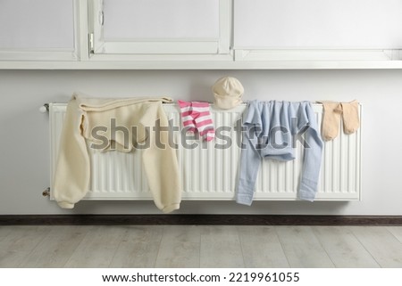 Clean clothes on heating radiator near window indoors