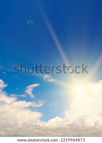 Beautiful, blue summer sky with fluffy clouds and bright sun as a background. Vertical photo.
