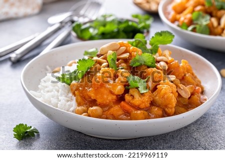 Vegan curry with cauliflower, chickpeas and butternut squash topped with peanuts, served with rice and cilantro Royalty-Free Stock Photo #2219969119