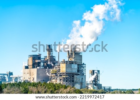 Industrial paper mill factory plant with chimney smokestacks stacks emitting carbon dioxide emission pollution in Georgetown, South Carolina town Royalty-Free Stock Photo #2219972417