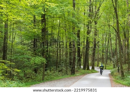 USA, Tennessee. Great Smoky Mountains National Park. Bicyclist on Cades Cove loop trail. (MR) Royalty-Free Stock Photo #2219975831