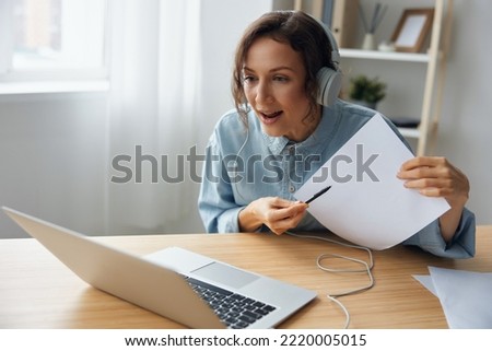 Angry boss businesswoman in headphones point pen at paper talk to subordinates about bad month result using laptop for remote meeting online. Irritated lady speak at web camera. Remote Job concept