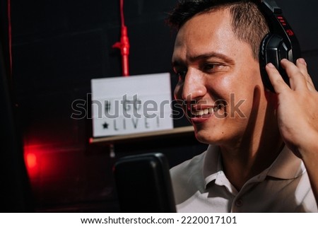 Host Talking and smiling on mic in a stream, podcast show, with headset (headphones) red and black background