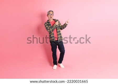 The full length of senior Asian man standing on the pink background.