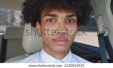 Attractive Black guy with Lush Curly Hair and pierced in the nose posing looking at cam. Handsome Male Smile sitting in car