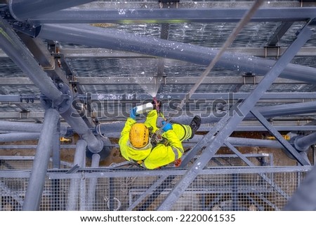 Rope access technicians clean the structure with a high-pressure cleaner