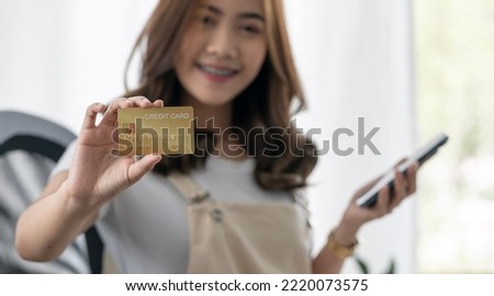 Smiling asian woman showing credit card, involved in online mobile shopping at home, happy female shopper purchasing online store.