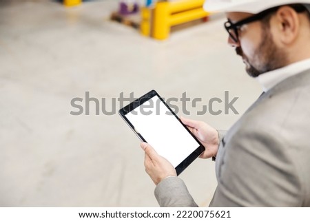 Image of a storage supervisor tracking inventory on tablet online while standing in facility.