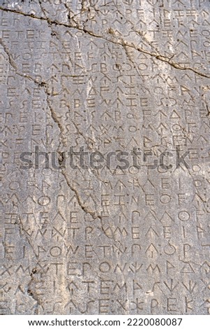 Ancient Greek antique text and inscriptions on the stone wall of the temple. Ancient Greek culture, alphabet and writing background, history concept.