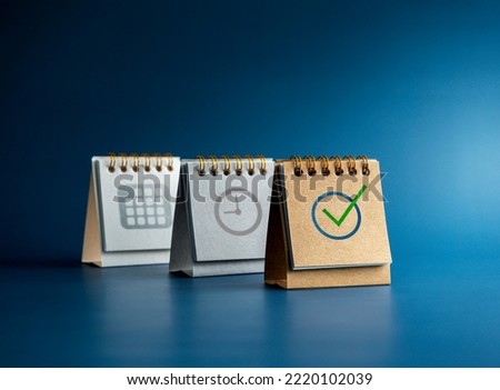 Checked icon, Time and date symbol on three desk calendar covers standing isolated on blue background, minimal style. Reminder, schedule planning, agenda, and action plan concepts. Royalty-Free Stock Photo #2220102039