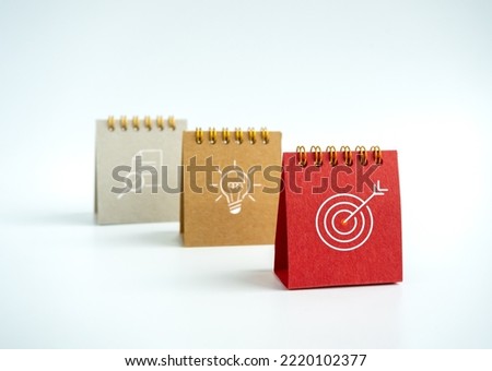 Business action plan with goal,  idea and research icon signs on small red, beige and grey desk calendar year 2023 on white background. Three step of strategy concept, minimal style. Royalty-Free Stock Photo #2220102377