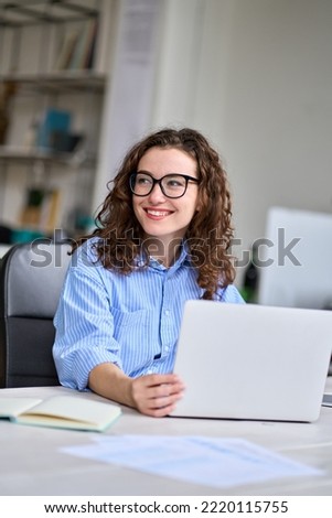 Young happy business woman company employee manager sitting at desk working on laptop. Pretty female professional worker using computer in corporate modern office looking away smiling. Vertical. Royalty-Free Stock Photo #2220115755