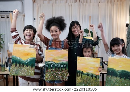 Group of art people in classroom studio, a teacher and student kids proud show painting work, an acrylic color picture on canvas, creative learning with talents skill at elementary school education. 