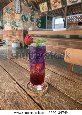 A glass of strawberry and eagle flower mocktail at cafe. Strawberry and mint as garnish. Es soda strawbery telang