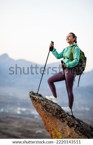 Hiker girl resting on a rock pedestal after long day trekking. Woman enjoying the sunset in nature. Royalty-Free Stock Photo #2220143511