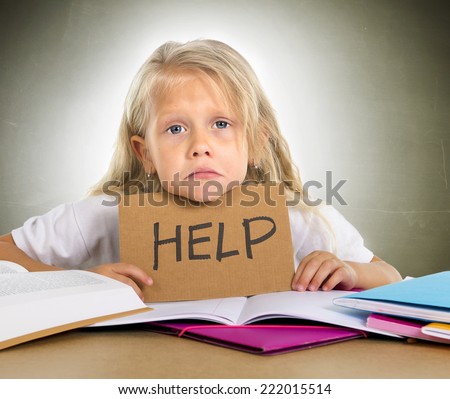cute little blonde hair schoolgirl sad and frustrated holding help sign in stress with books and homework in children education concept isolated on grunge studio background