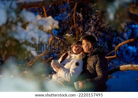 A couple in love enjoys each other walking in the winter woods in the evening.