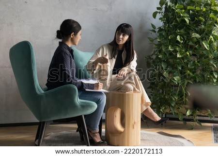 50s businesswoman talks to intern sit on armchairs in office, experienced mentor gives professional advices to apprentice, boss make assignments to secretary, subordinate listen to chief, writes tasks Royalty-Free Stock Photo #2220172113