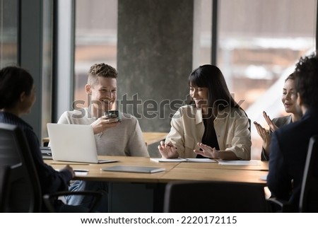 Group of smiling colleagues sit at table gathered in modern boardroom, brainstorm, discuss project joking and laughing, having fun, cooperating together at office meeting. Teamwork, break, friendship Royalty-Free Stock Photo #2220172115