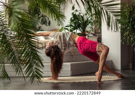 Young attractive woman practices yoga at home,dancing dog pose,doing Camatkarasana exercise.Relaxation and meditation.Wellness,wellbeing,mental health concept.Selective focus. Royalty-Free Stock Photo #2220172849