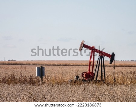Pumpjack for extraction of crude oil near a corn field on an October morning in rural southeastern Illinois, USA. Foreground focus. For themes of energy, resources, and the environment.