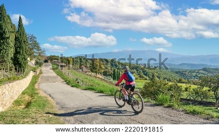 nice senior woman riding her electric mountain bike between olive trees near Arezzo,Tuscany , Italy