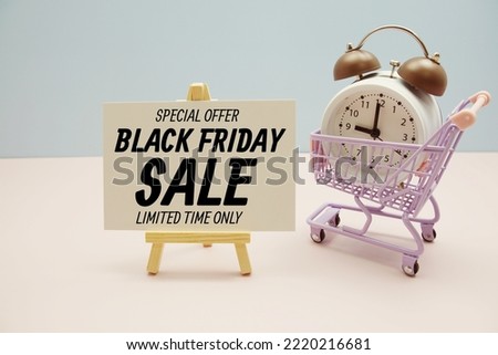 Black Friday Sale text message for promotion with alarm clock and shopping trolley cart on pink and blue background