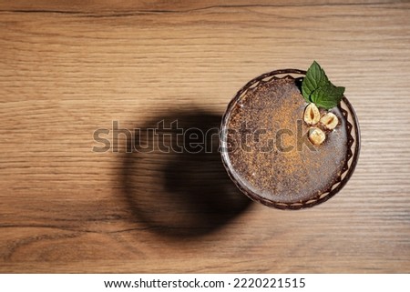 Dessert bowl of delicious hot chocolate with hazelnuts and fresh mint on wooden table, top view. Space for text